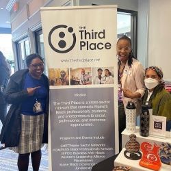 Three smiling people stand in front of a "Third Place" banner