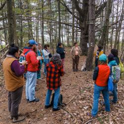 A group of people standing together in a forest surrounded by tall trees