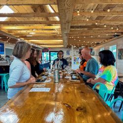A group of people around a wooden table site with sample platters in front of them