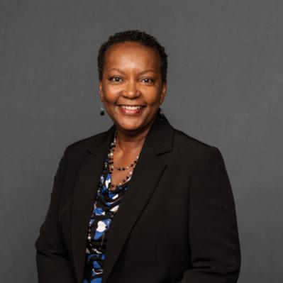 Idella smiling with a black blazer and long necklace